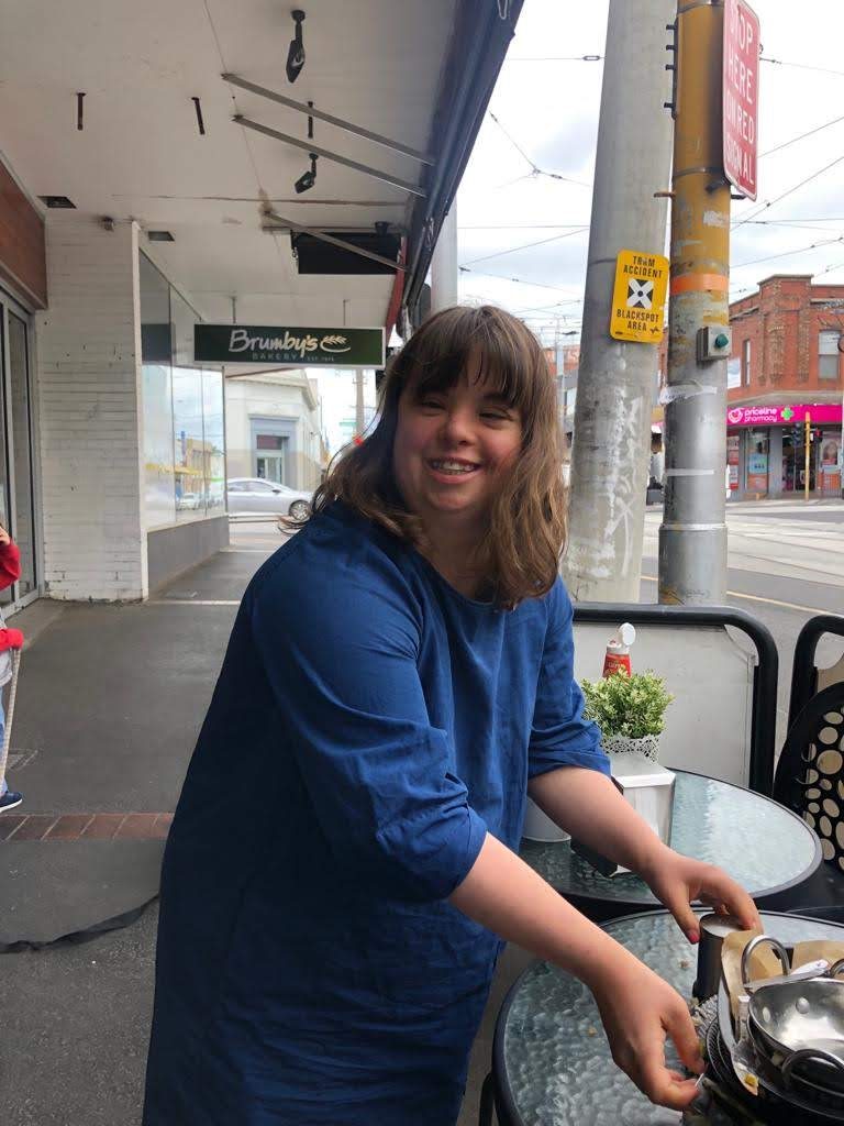 Rachel smiling at an outdoor café table on a Melbourne street